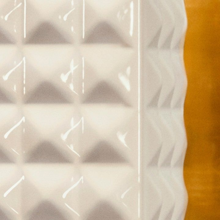 A woman wearing black lace-patterned gloves held a SPIKE VALENTINO IVORY, pressing the keys of a vintage telephone.